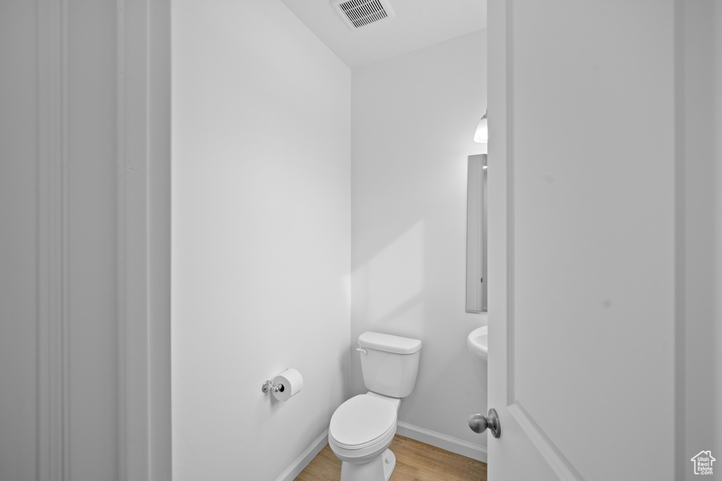 Bathroom featuring wood finished floors, toilet, and baseboards
