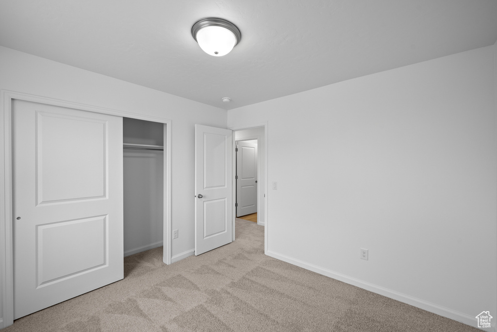Unfurnished bedroom featuring carpet floors, baseboards, and a closet