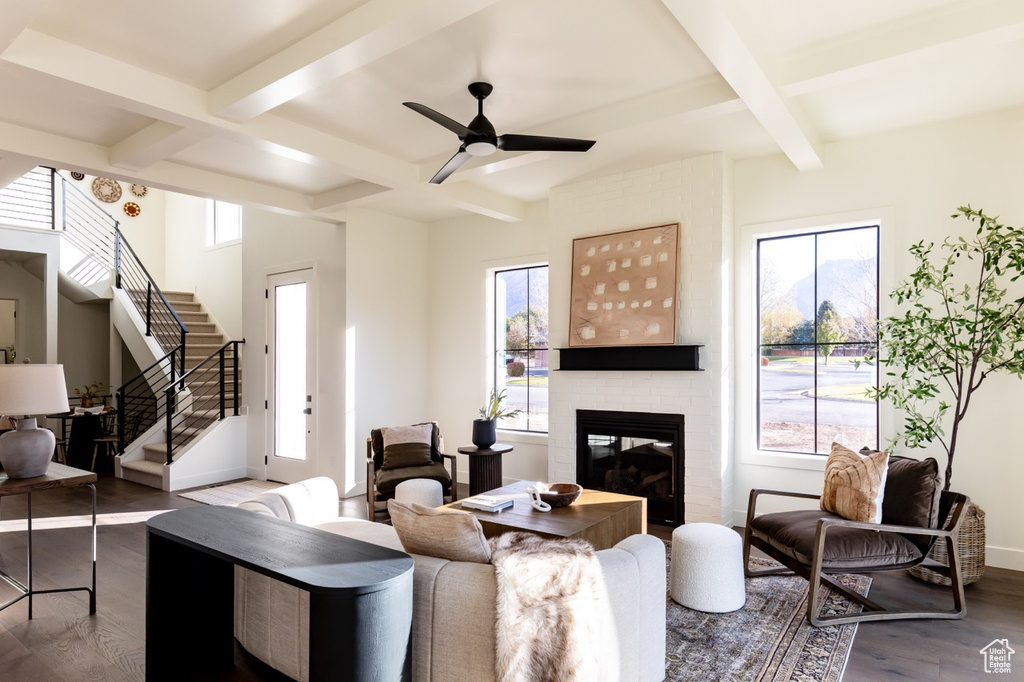 Living room featuring a wealth of natural light, hardwood / wood-style floors, a brick fireplace, and ceiling fan