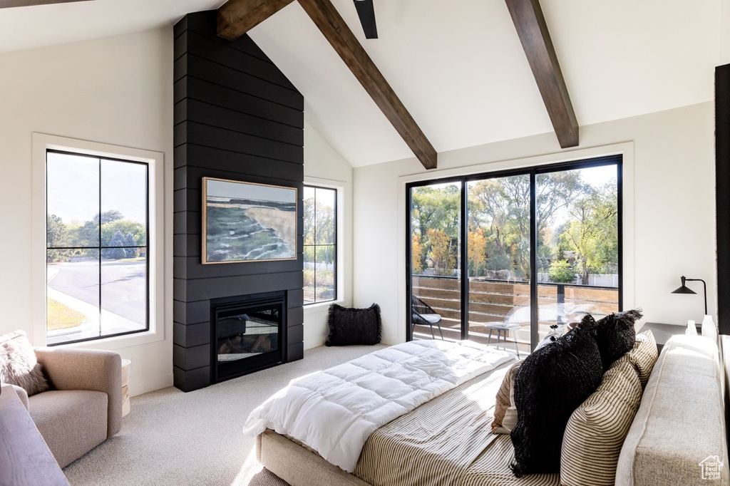 Bedroom featuring light carpet, multiple windows, beamed ceiling, and a fireplace