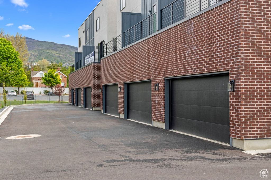 View of property with a mountain view, an attached garage, and driveway