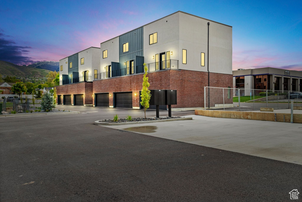 View of building exterior featuring fence, an attached garage, and driveway