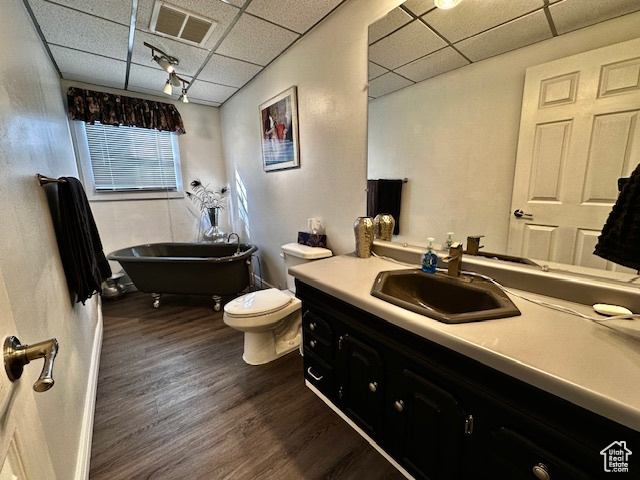 Bathroom with hardwood / wood-style floors, a paneled ceiling, toilet, a bath, and vanity