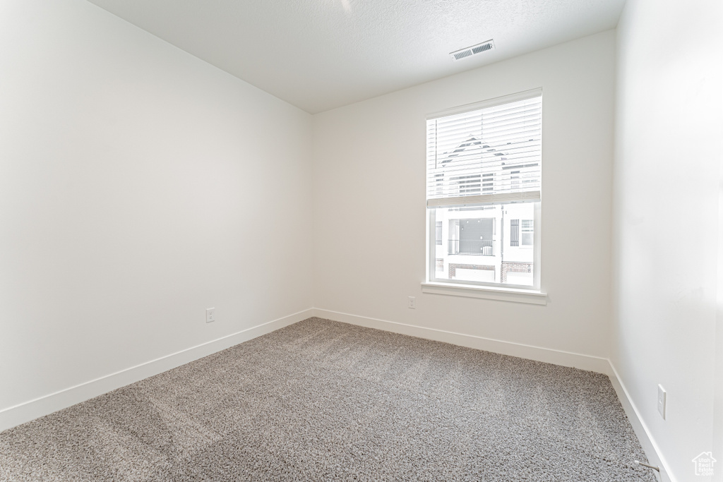 Empty room with baseboards, visible vents, carpet, and plenty of natural light