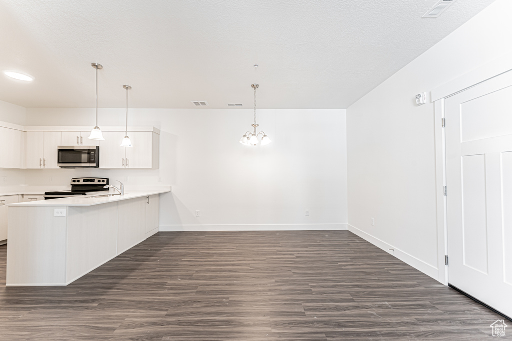Kitchen featuring light countertops, appliances with stainless steel finishes, a peninsula, visible vents, and white cabinets