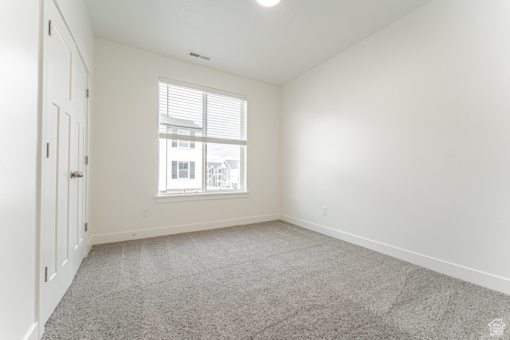 Empty room featuring baseboards, carpet flooring, and visible vents