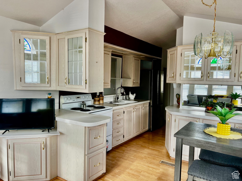 Kitchen featuring vaulted ceiling, light countertops, electric range, and a sink