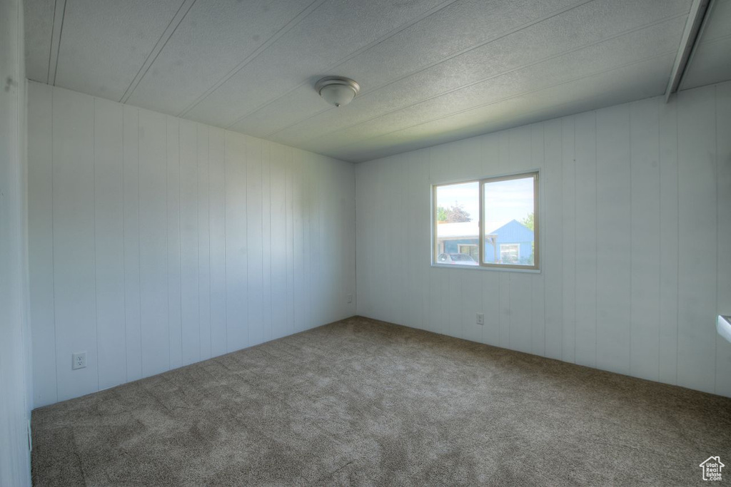 Carpeted empty room featuring wood walls