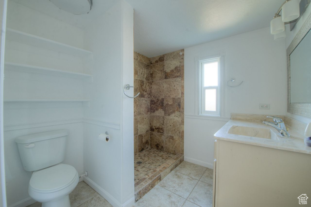 Bathroom featuring vanity, toilet, tiled shower, and tile patterned flooring