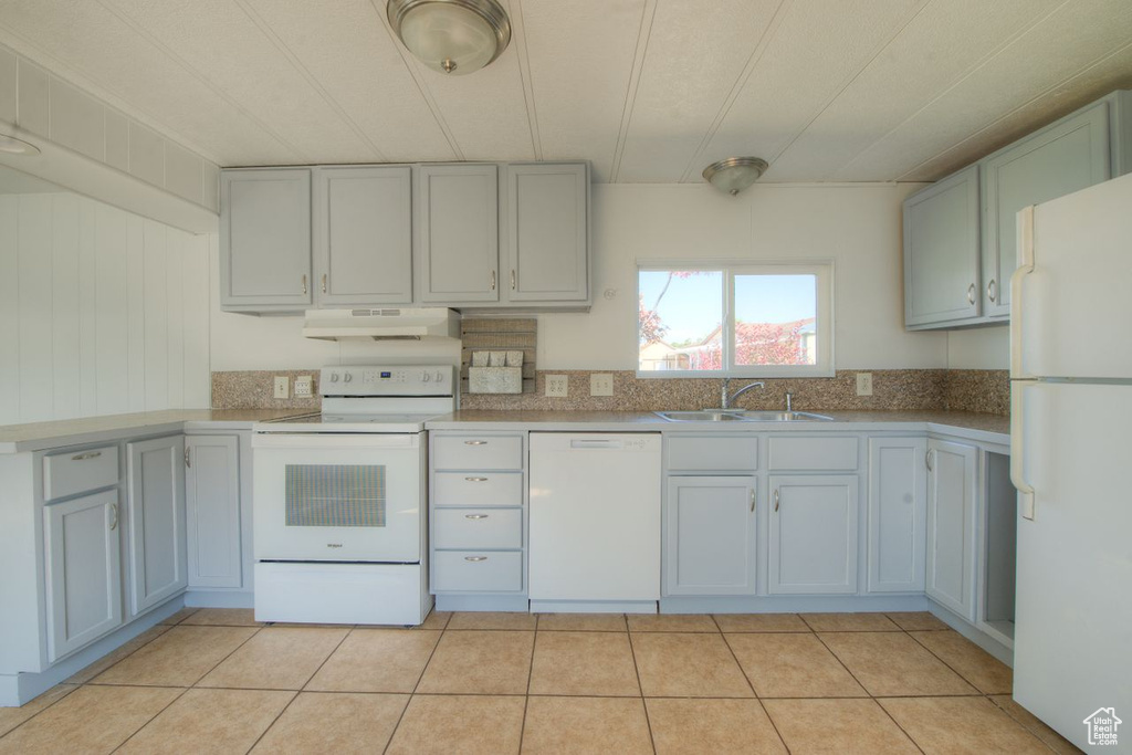 Kitchen with wooden walls, sink, white appliances, and light tile patterned floors