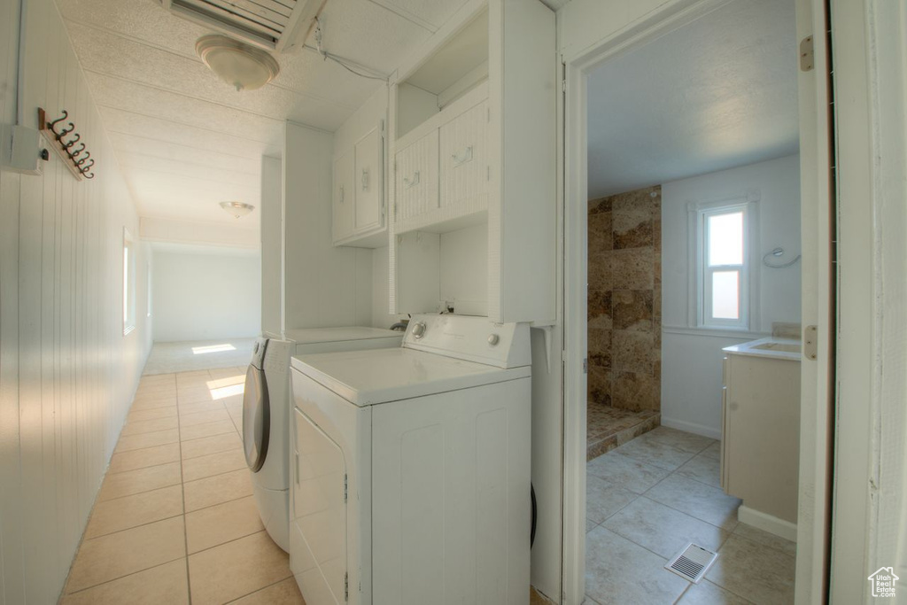 Laundry area with wooden walls, washing machine and dryer, and light tile patterned floors
