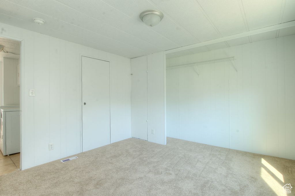 Unfurnished bedroom with light colored carpet and washer / clothes dryer