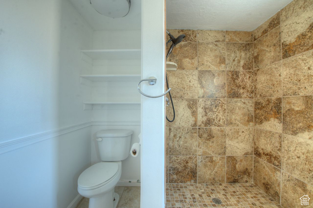 Bathroom featuring a tile shower and toilet