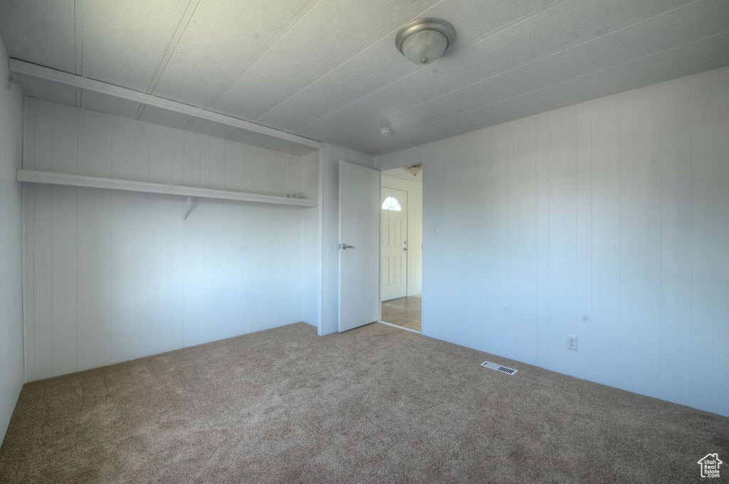 Unfurnished bedroom featuring carpet floors and wood walls