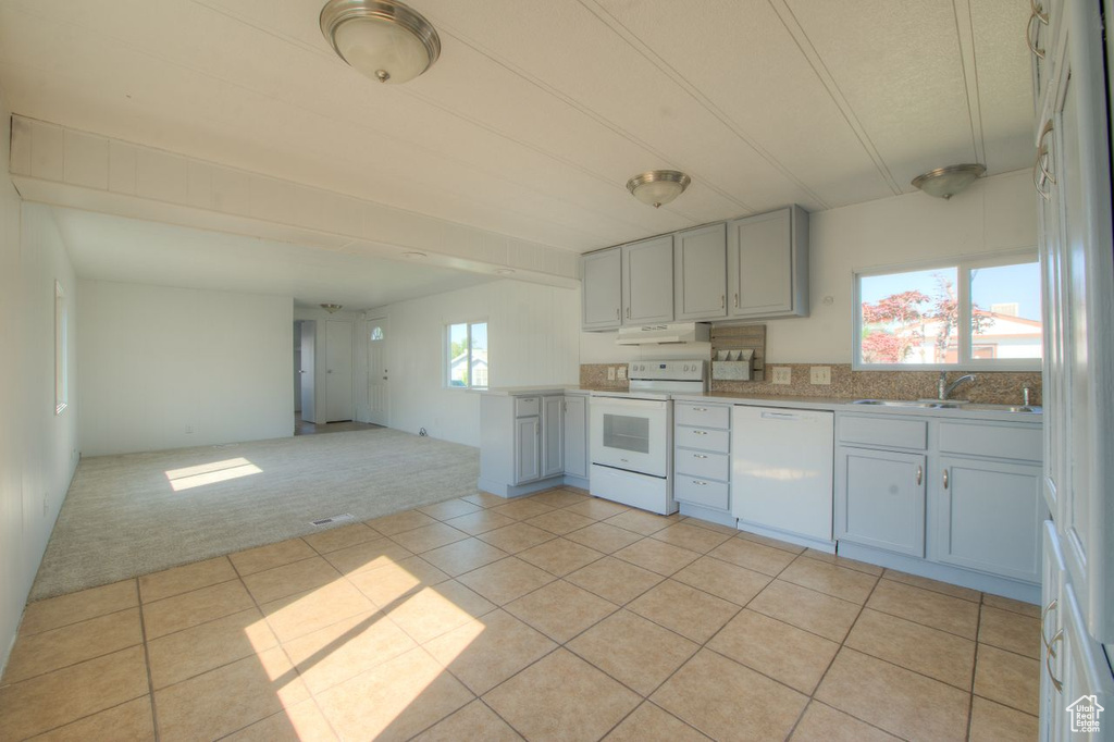 Kitchen featuring white appliances, sink, and light colored carpet