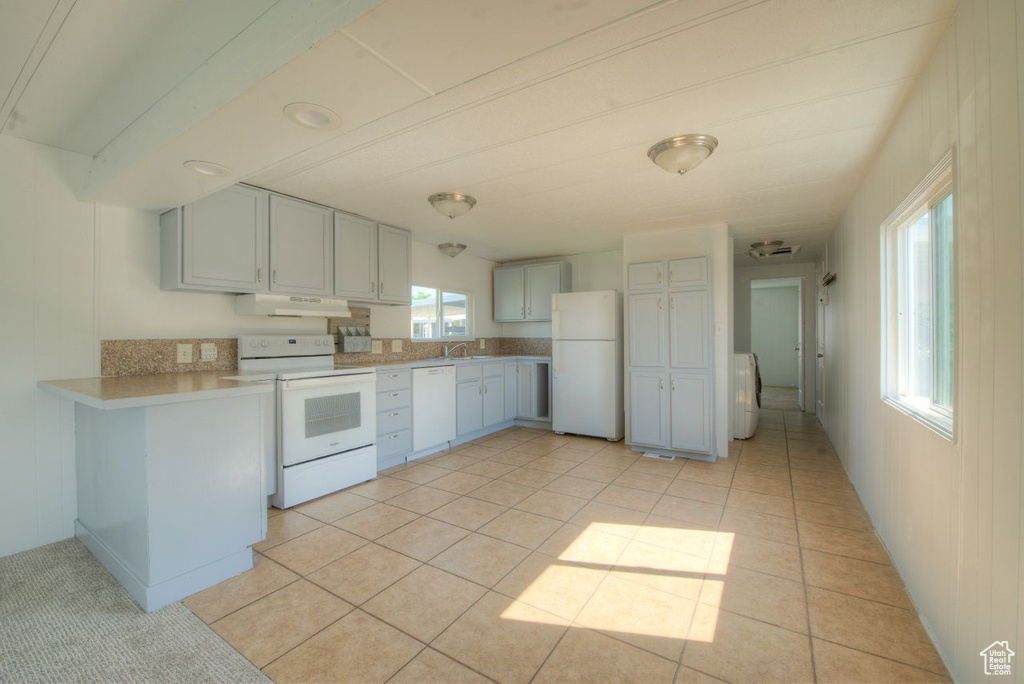Kitchen featuring a wealth of natural light, light tile patterned floors, and white appliances