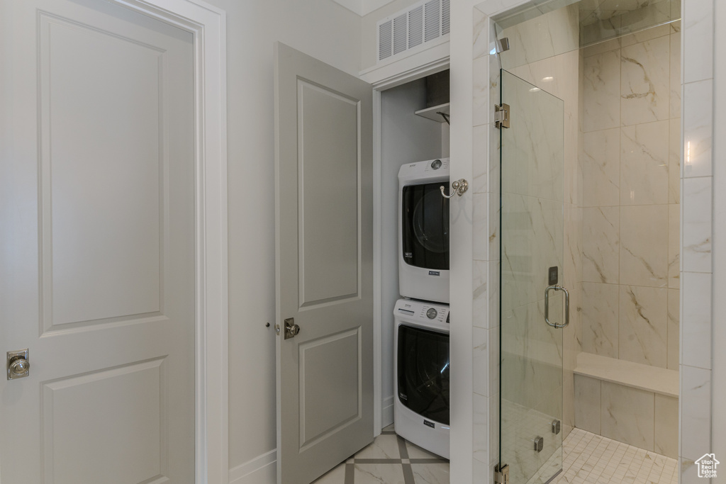 Bathroom featuring tile patterned floors, stacked washing maching and dryer, and walk in shower