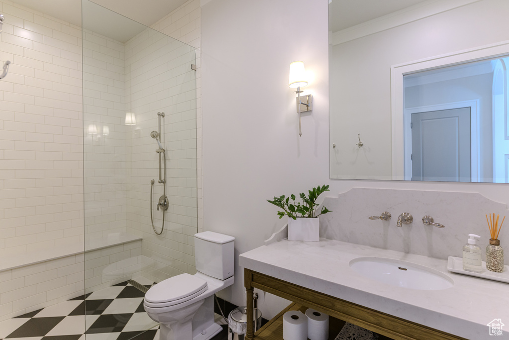 Bathroom with vanity, toilet, ornamental molding, and tiled shower