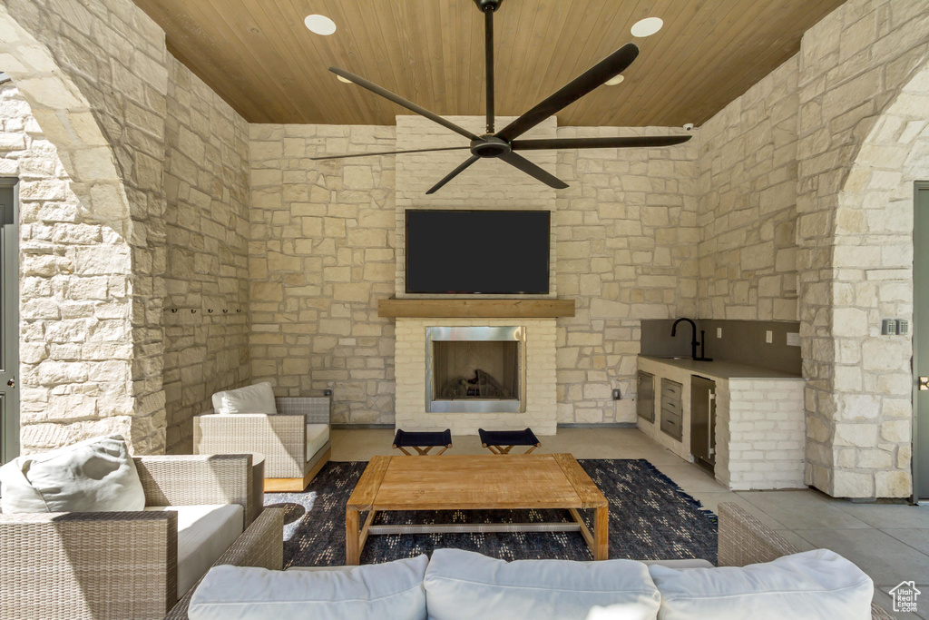 Living room with sink, wooden ceiling, an outdoor fireplace, and ceiling fan