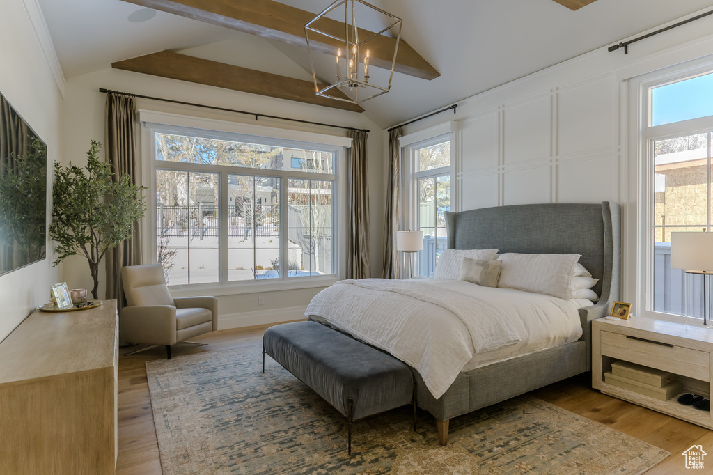 Bedroom featuring light hardwood / wood-style floors, lofted ceiling, and an inviting chandelier