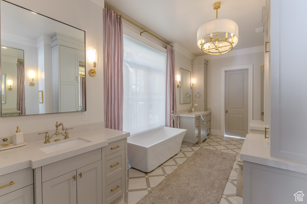 Bathroom with a tub to relax in, vanity, crown molding, an inviting chandelier, and tile patterned flooring