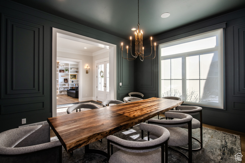 Dining space featuring crown molding, a healthy amount of sunlight, built in shelves, and hardwood / wood-style floors