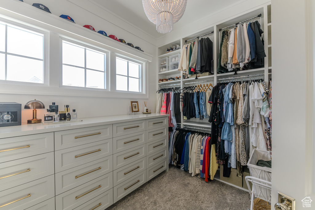 Walk in closet featuring light colored carpet and an inviting chandelier