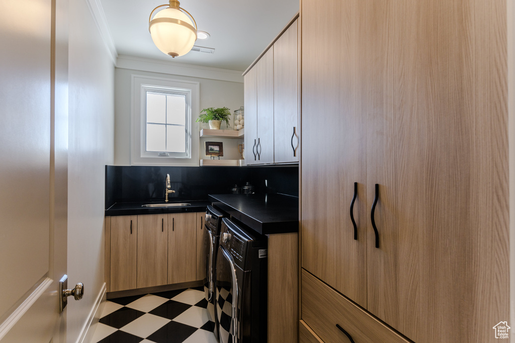 Kitchen featuring crown molding, washer and dryer, and sink