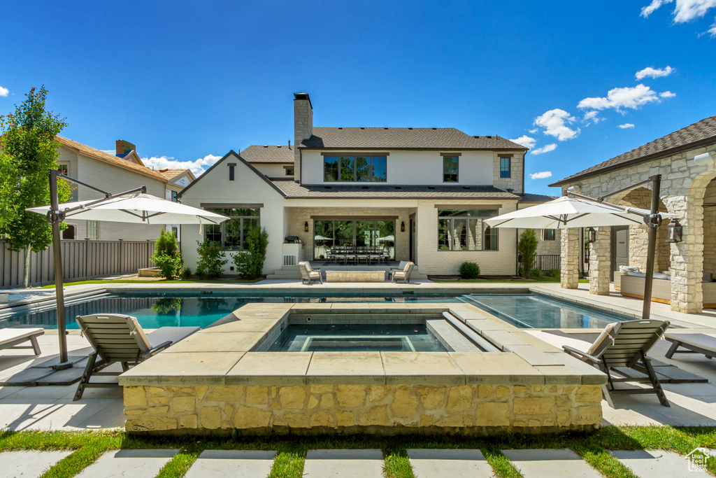 Back of property featuring a patio area and a pool with hot tub