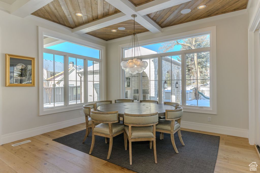 Dining space with beamed ceiling, a notable chandelier, light hardwood / wood-style floors, and wooden ceiling