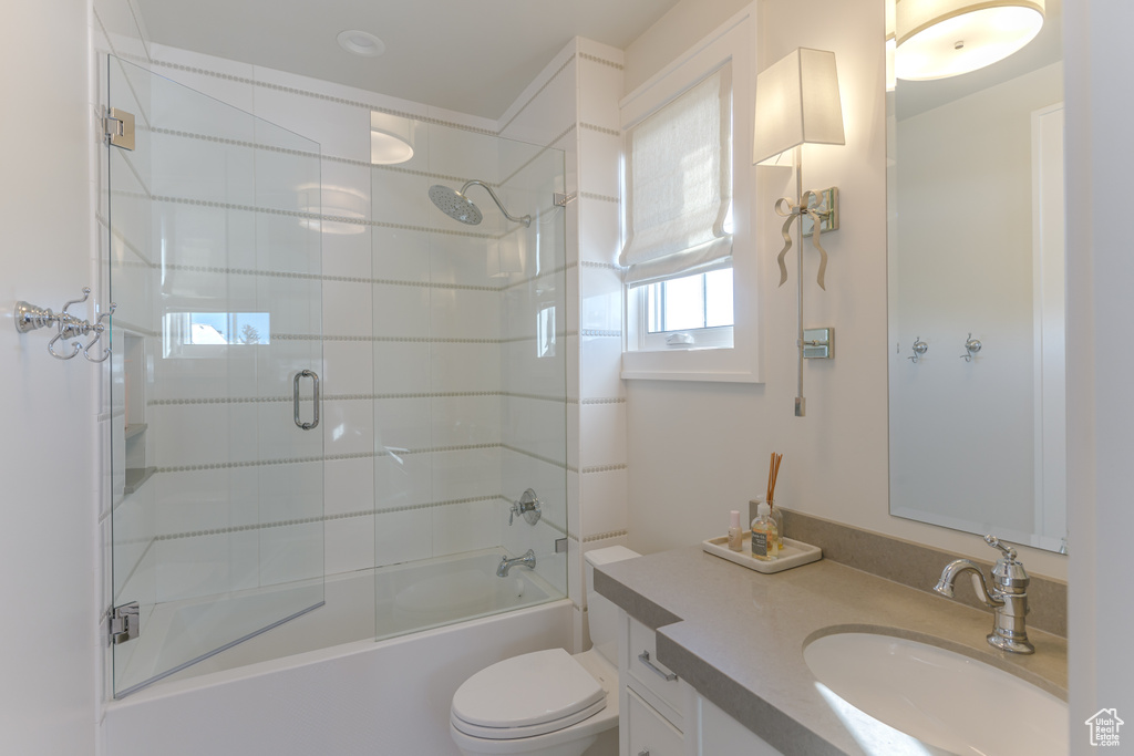 Full bathroom with vanity, bath / shower combo with glass door, and toilet