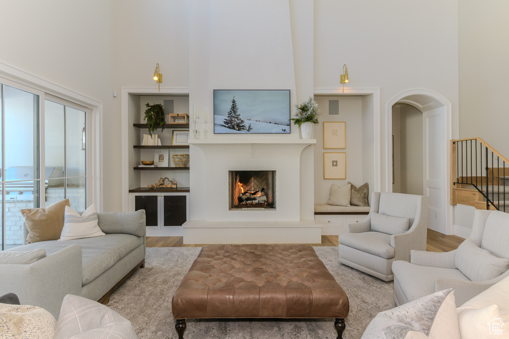 Living room with a towering ceiling, hardwood / wood-style floors, and built in features