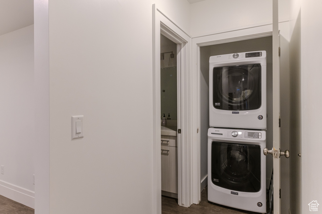 Laundry room with dark wood-type flooring and stacked washing maching and dryer