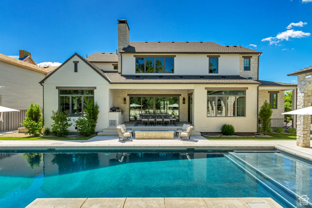 Rear view of house featuring an outdoor living space, a patio area, and a fenced in pool