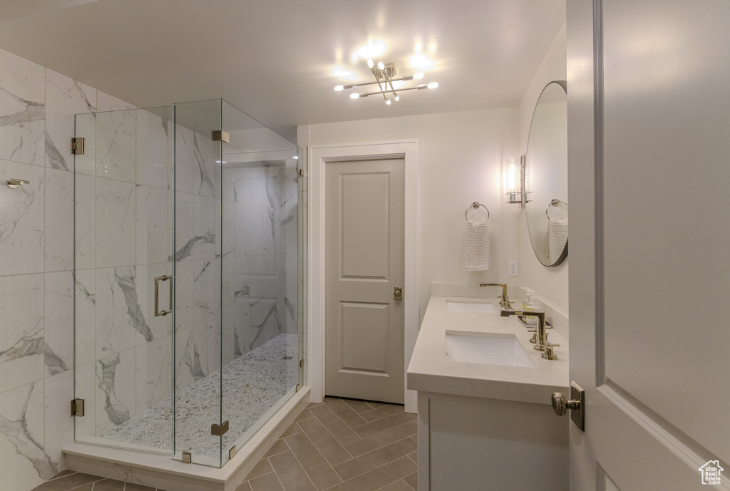 Bathroom featuring vanity, a notable chandelier, tile patterned flooring, and walk in shower