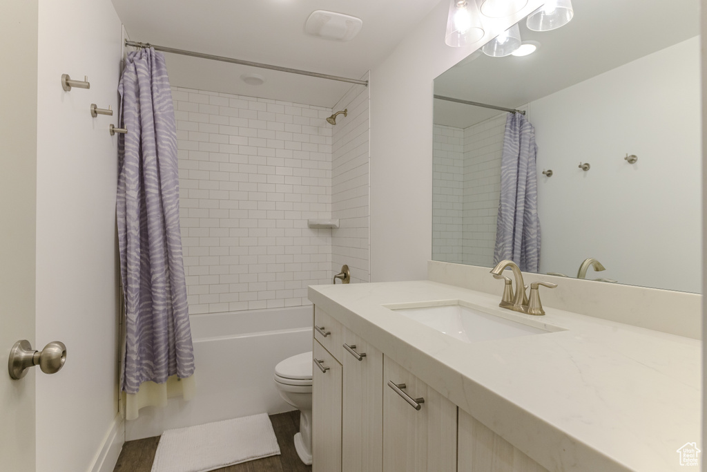 Full bathroom with toilet, shower / bath combo with shower curtain, vanity, and wood-type flooring