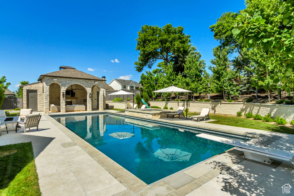 View of pool with a patio, a gazebo, a diving board, and an outbuilding