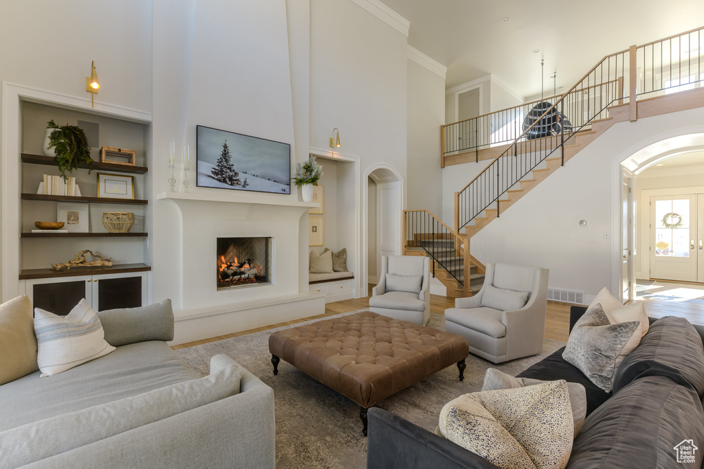 Living room with crown molding, a towering ceiling, and wood-type flooring