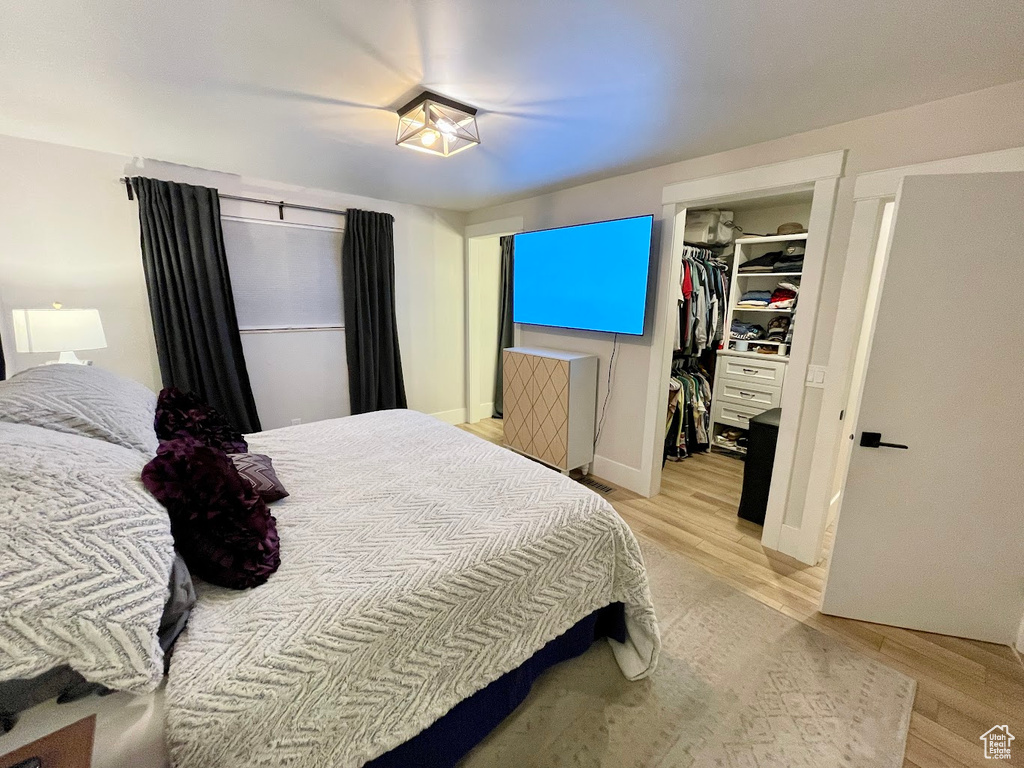 Bedroom with light hardwood / wood-style floors, a spacious closet, and a closet