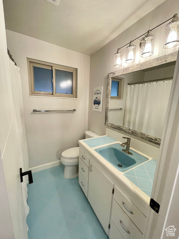 Bathroom with toilet, vanity, and tile patterned flooring