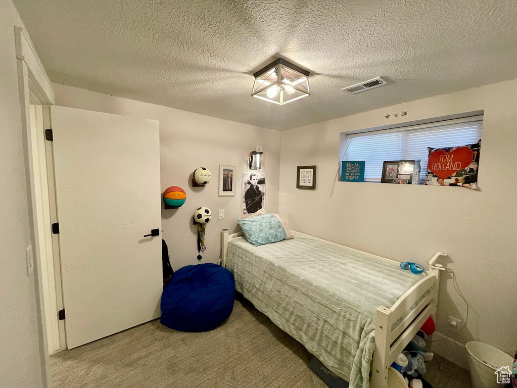 Bedroom with a textured ceiling and carpet flooring