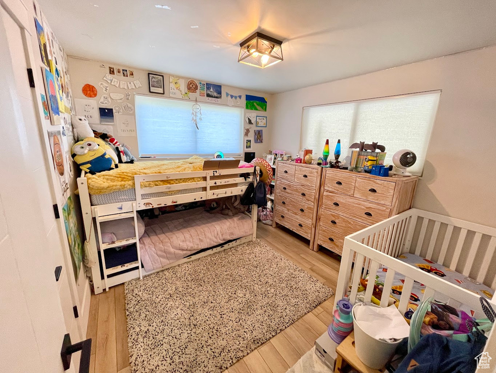 Bedroom featuring light wood-type flooring and a crib