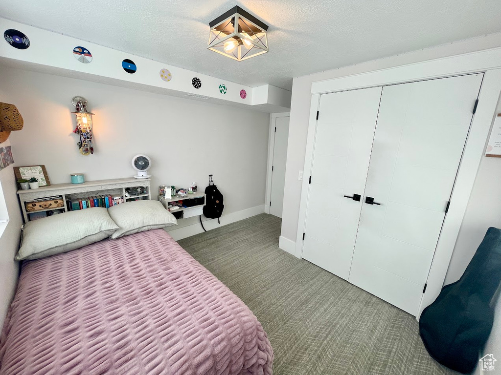 Carpeted bedroom featuring a textured ceiling and a closet