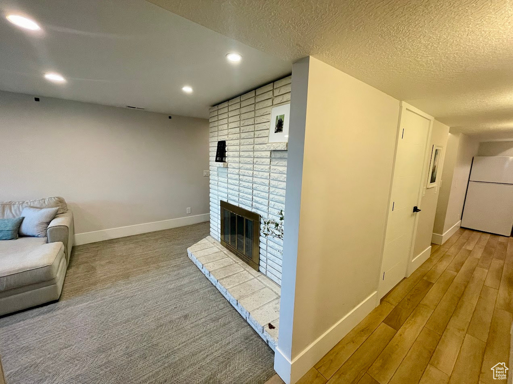 Living room featuring light hardwood / wood-style flooring, a textured ceiling, and a fireplace