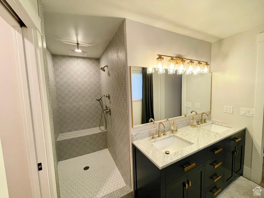 Bathroom featuring tiled shower and vanity