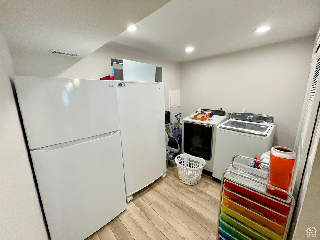 Laundry area featuring independent washer and dryer and light hardwood / wood-style floors