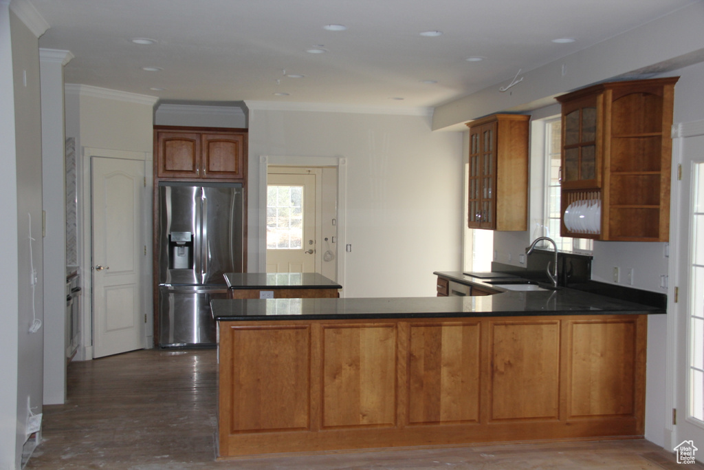 Kitchen with dark wood-type flooring, kitchen peninsula, stainless steel refrigerator with ice dispenser, and sink