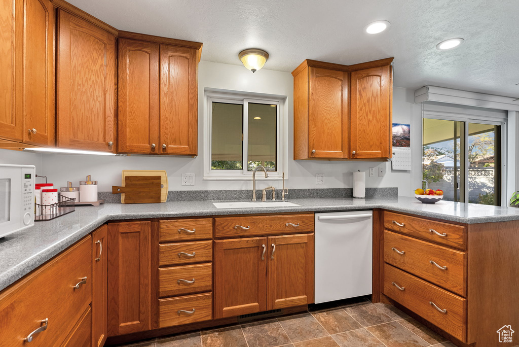 Kitchen with white appliances, sink, and a textured ceiling