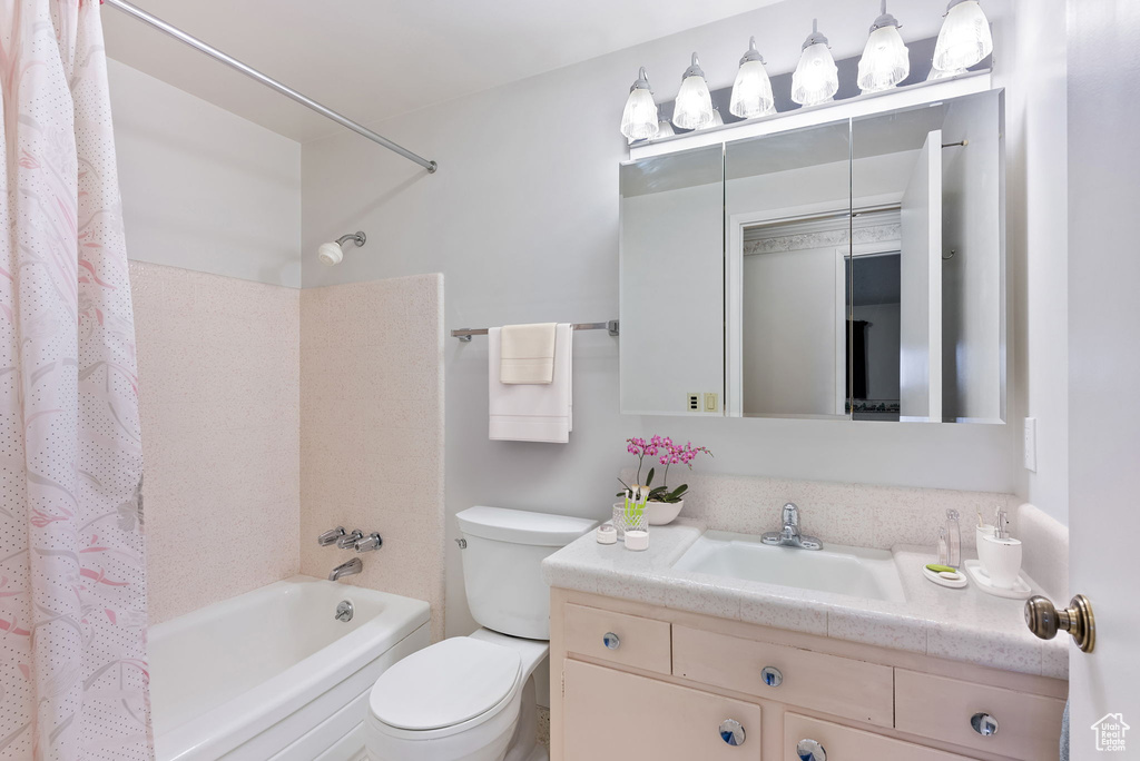 Full bathroom with toilet, shower / tub combo with curtain, and vanity