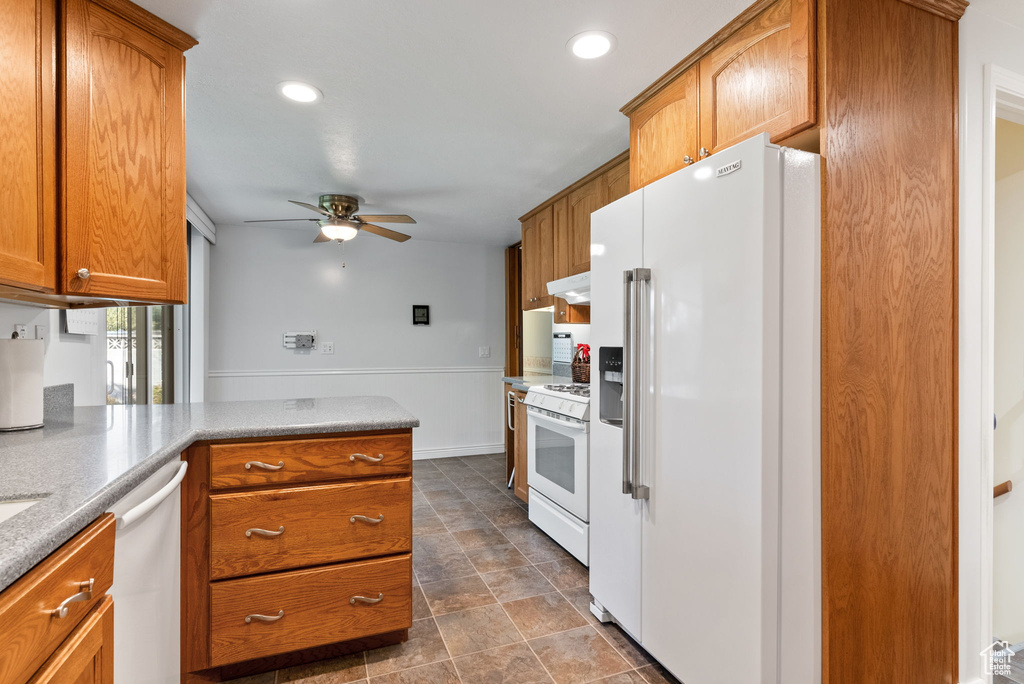 Kitchen featuring kitchen peninsula, ceiling fan, white appliances, and ventilation hood